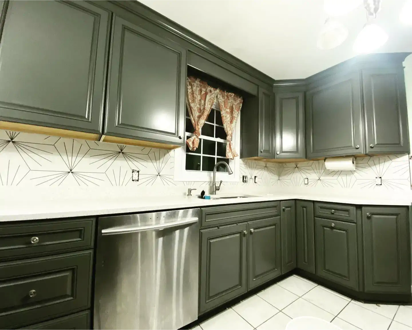 A kitchen with gray cabinets and a stainless steel dishwasher.