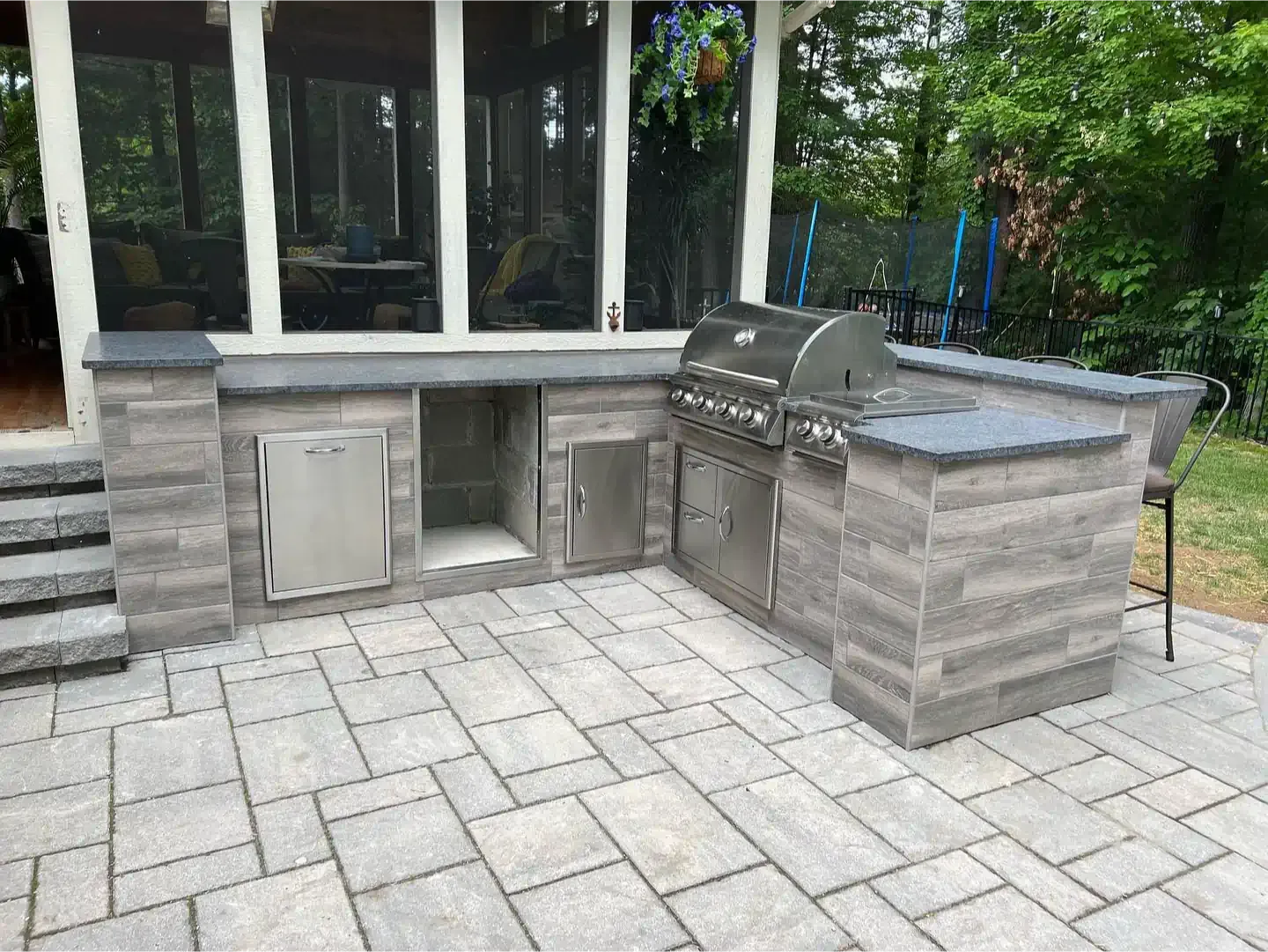 A large outdoor kitchen with a grill and a sink on a patio.