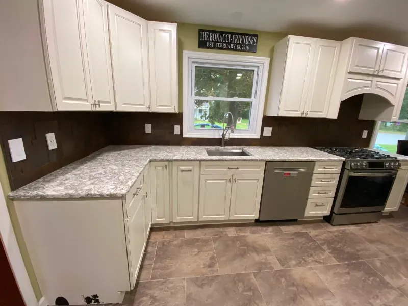 A kitchen with white cabinets , granite counter tops , a stove and a sink.