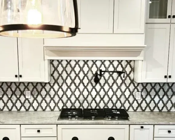 A kitchen with white cabinets , a stove top oven , and a pendant light.