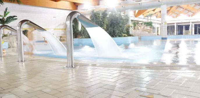 There is a waterfall in the middle of a swimming pool.