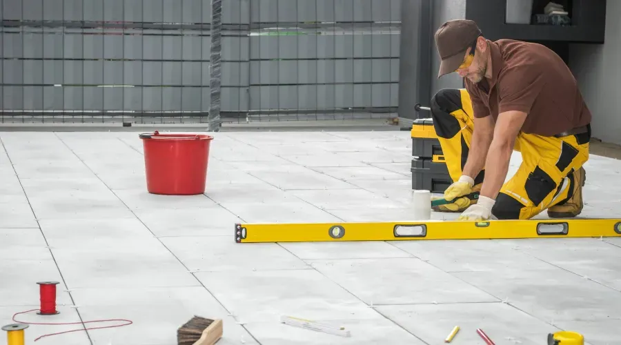A man is measuring a tile floor with a level.