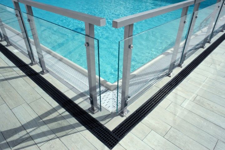 Glass panels secured to a metal railing around a pool edge