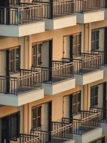 Apartment balconies with black railings on a beige building facade