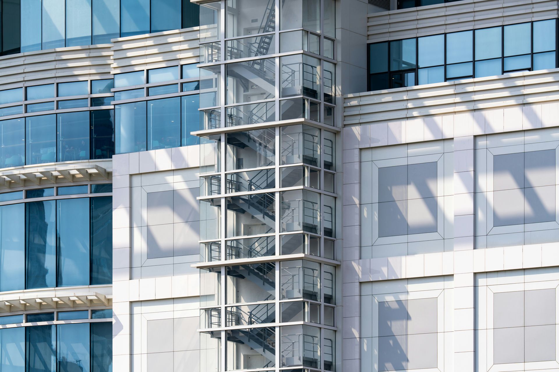 Modern building facade with blue glass windows and a central metal scaffold structure