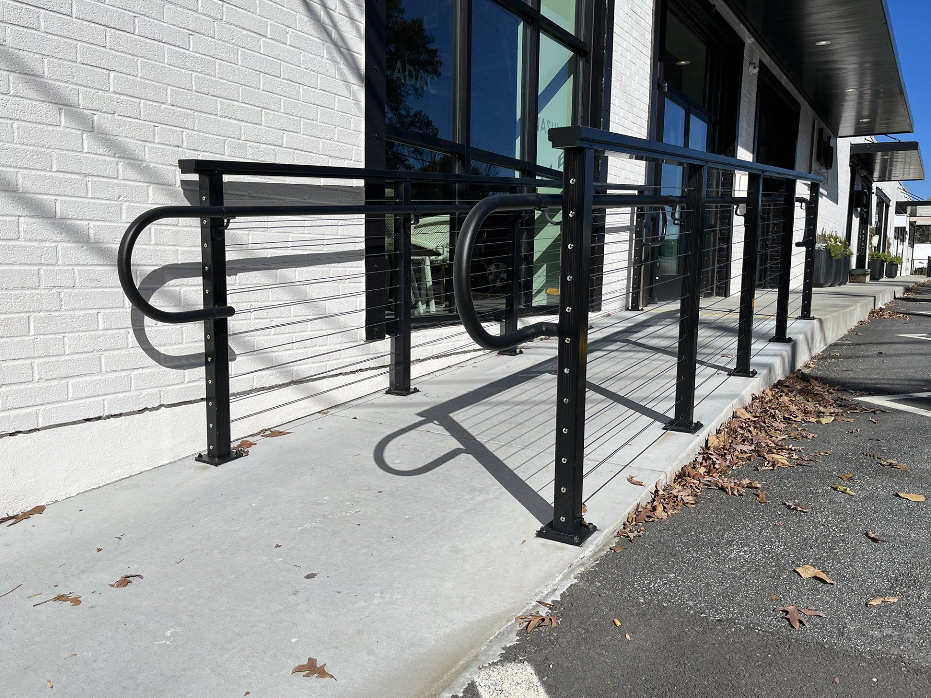 black aluminum railing along ramp on walkway at strip mall