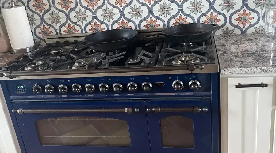A blue stove with two pans on top of it in a kitchen.