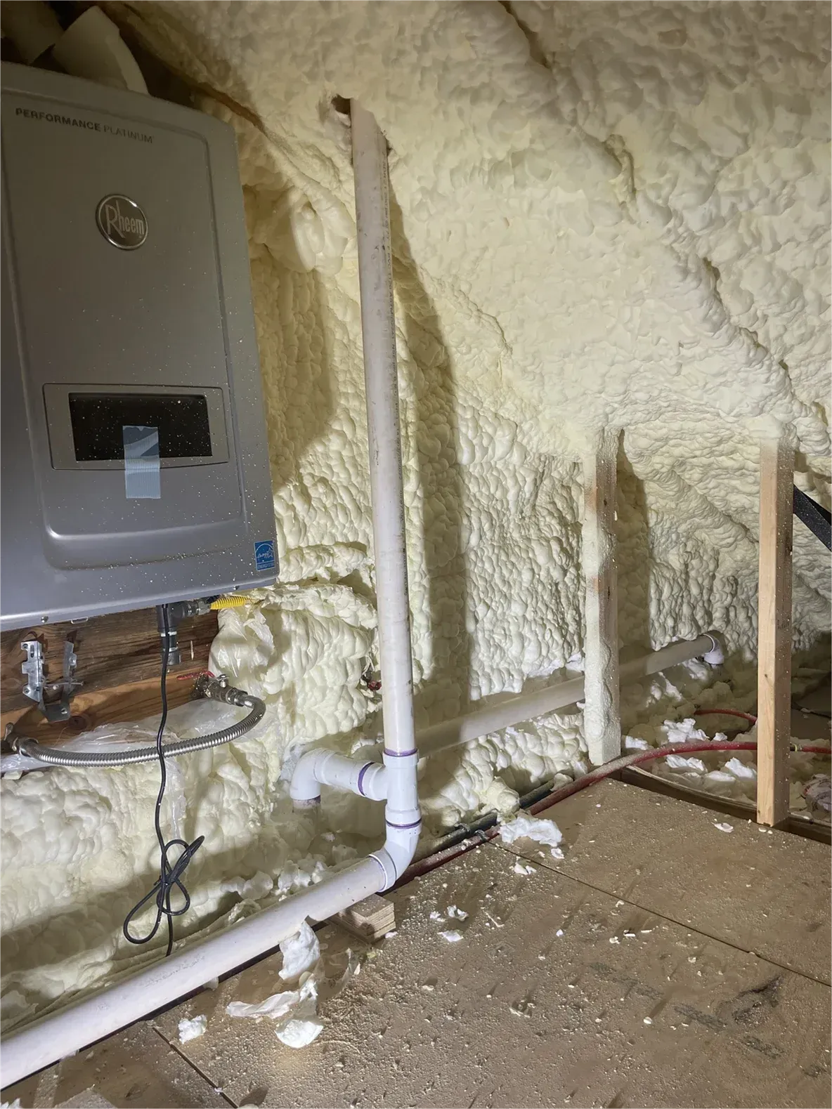 A room with a boiler and pipes covered in foam.