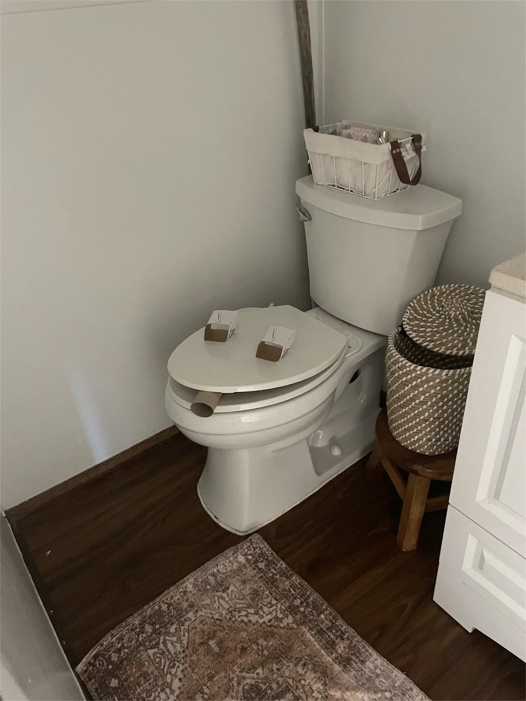 A toilet in a bathroom with a basket on top of it.