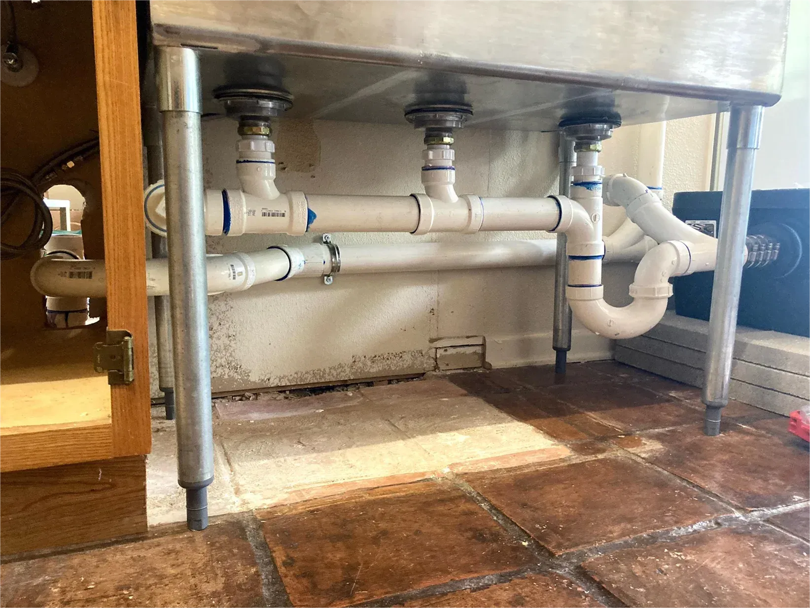 A kitchen sink with a lot of pipes underneath it.