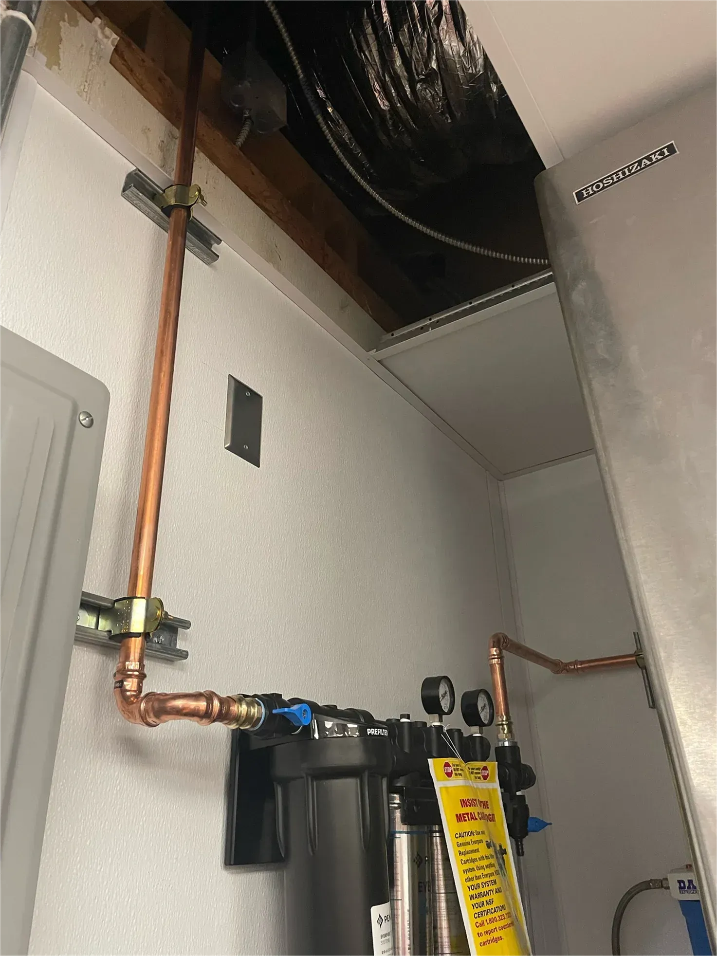 A copper pipe is hanging from the ceiling of a room.