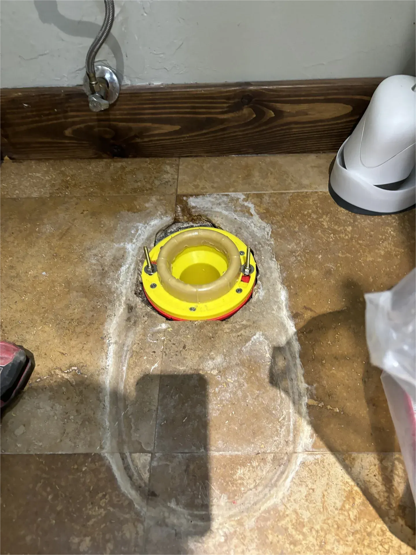 A yellow toilet flange is sitting on the floor in a bathroom.