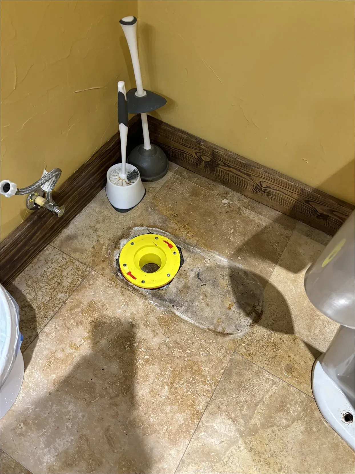 A toilet is sitting on a tiled floor next to a toilet brush.