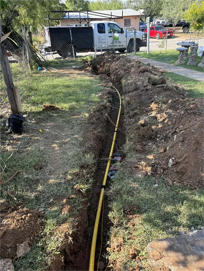 A white truck is parked in the dirt next to a yellow hose.