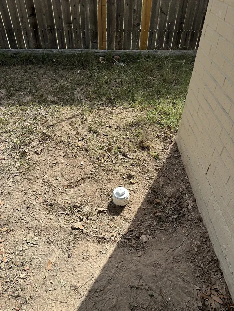 A white ball is sitting on the ground next to a brick wall.