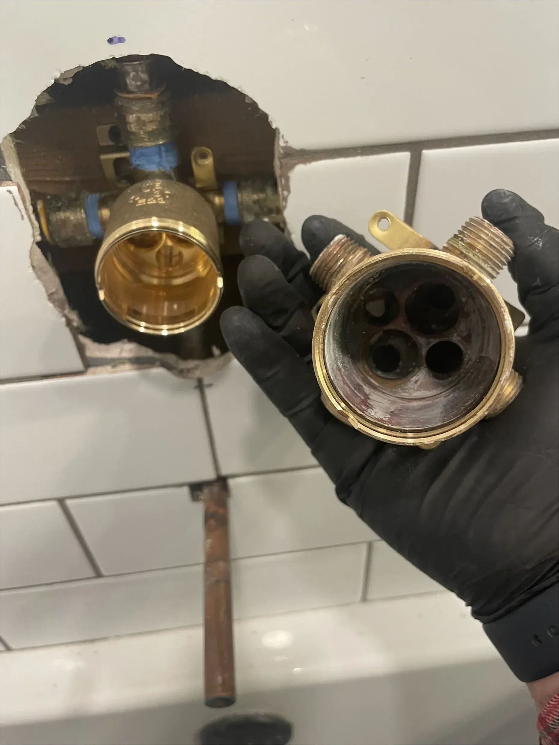 A person wearing black gloves is holding a piece of metal in their hand.