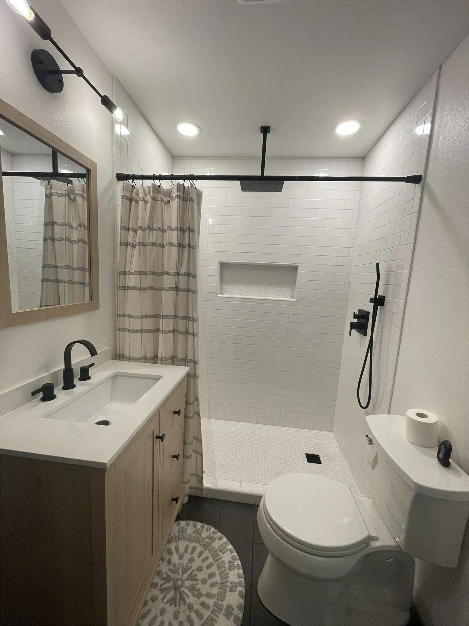 A bathroom with a toilet , sink and shower.