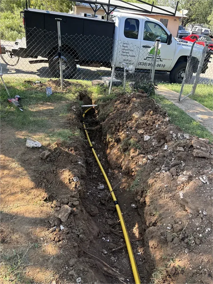 A white truck is parked in the dirt next to a yellow pipe.