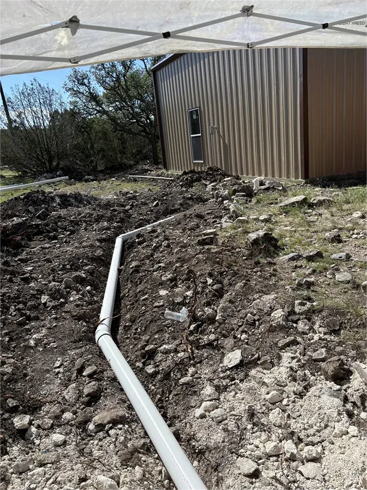 A pipe is laying in the dirt in front of a building.