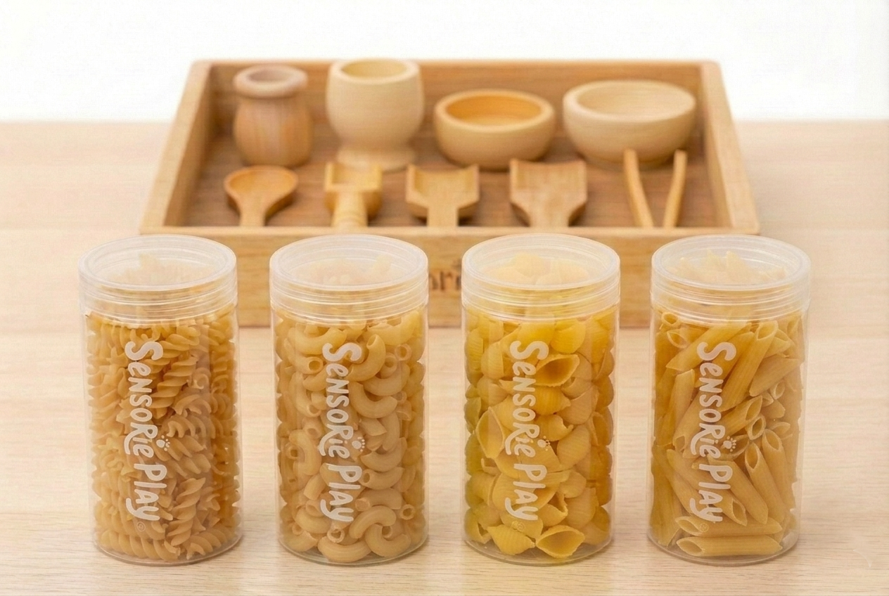 Four clear spice jars with dried ingredients beside a wooden spice rack and utensils
