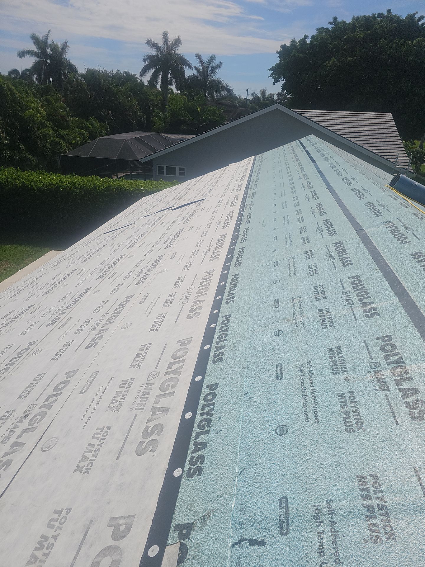 Two white and light blue roofing panels installed on a sloped roof under a sunny sky.