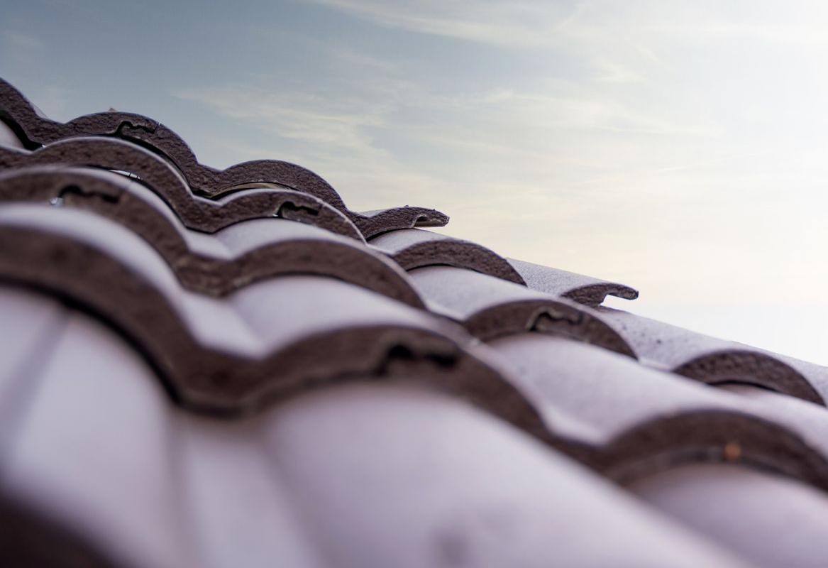 Close-up of curved terracotta roof tiles against a cloudy sky