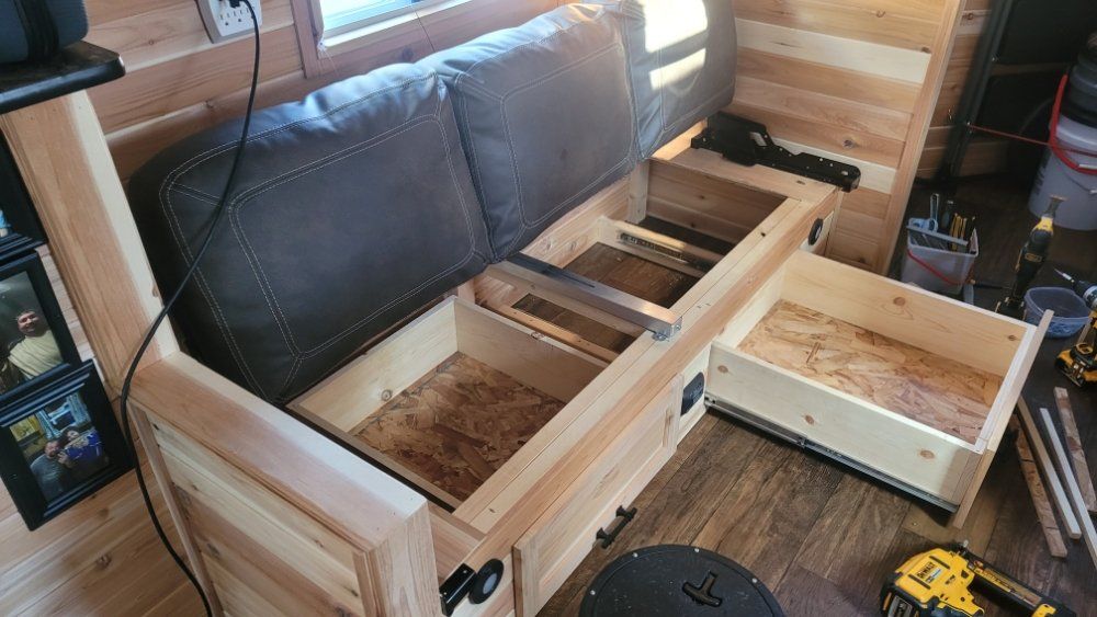 Wooden bench with open storage, revealing drawers and a lift-up seat. Interior setting.