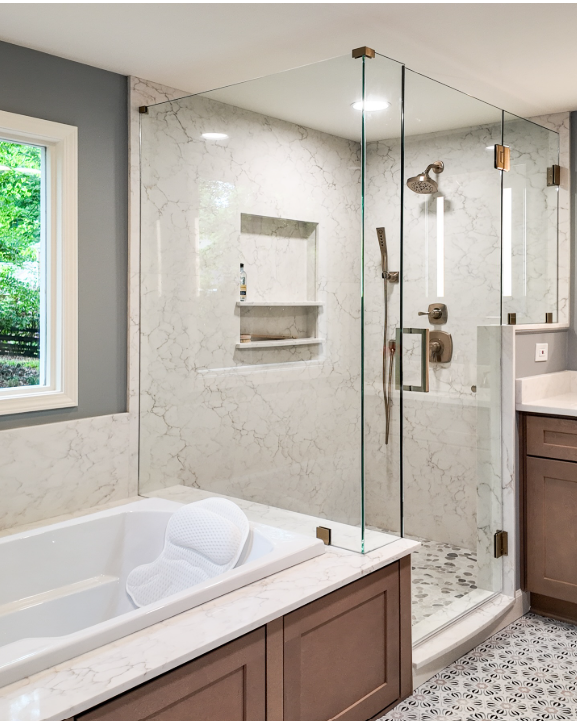 Modern bathroom with glass shower, marble tile, and a white tub with wood vanity.