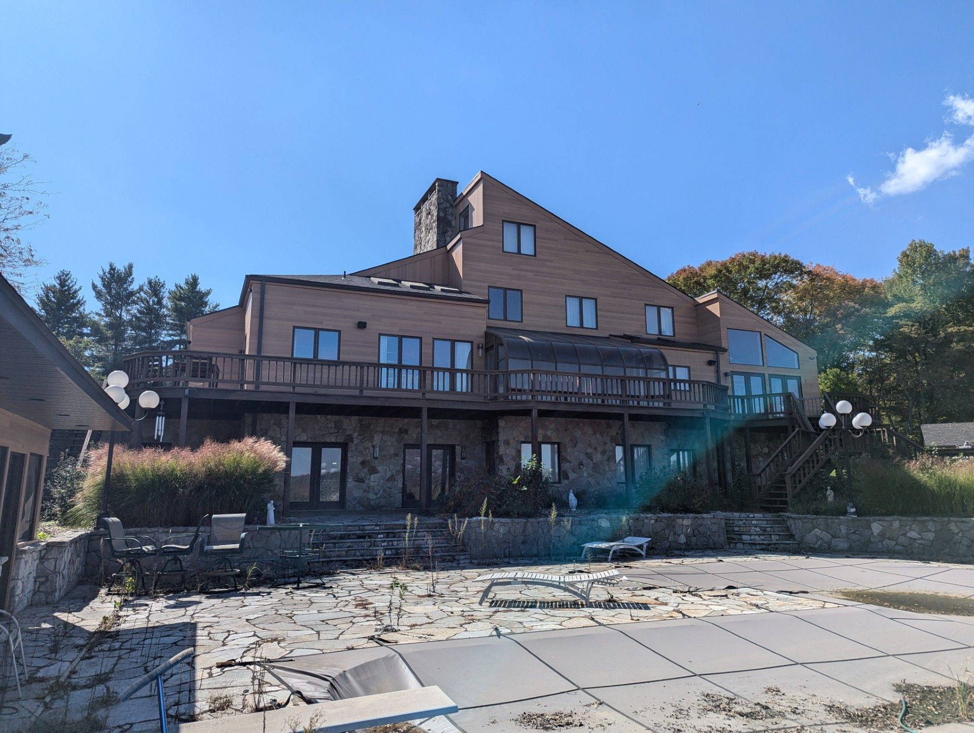 Large wooden lodge with balconies on a rocky waterfront under a clear blue sky.