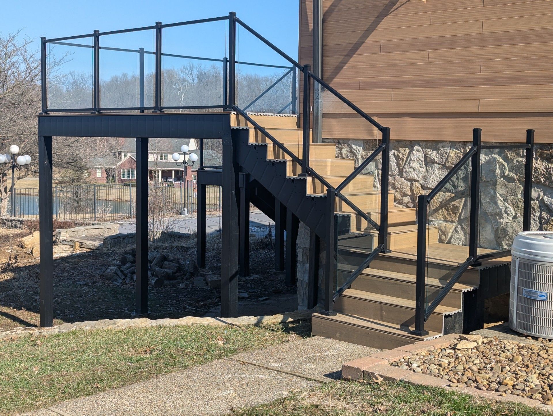 Outdoor wooden stairs and raised deck with black railings beside a building.