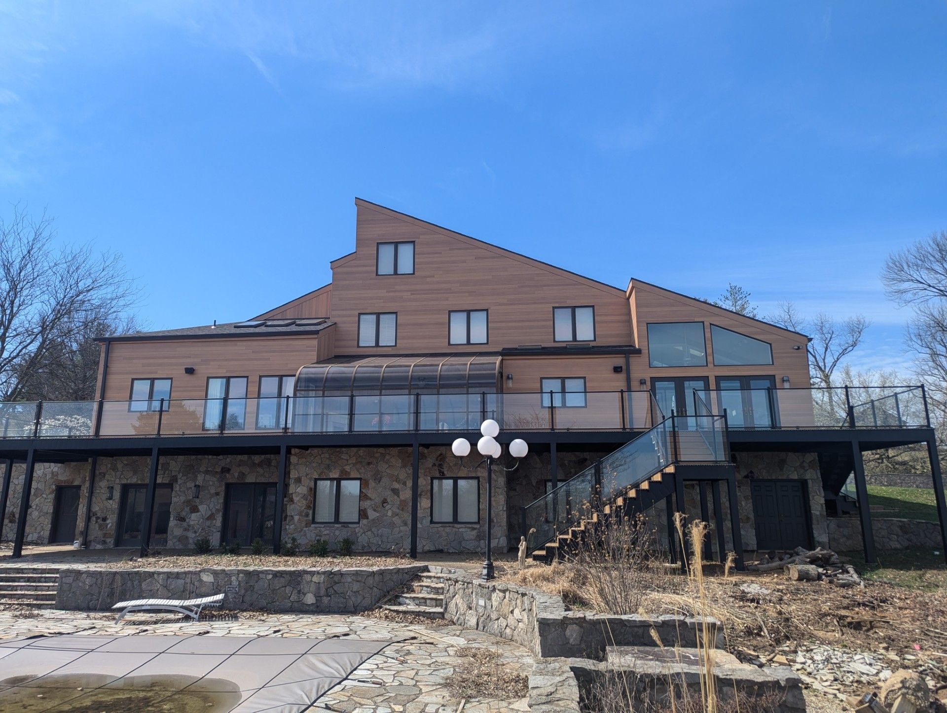Large multi-story building with wood siding, stone base, and stairs under a blue sky