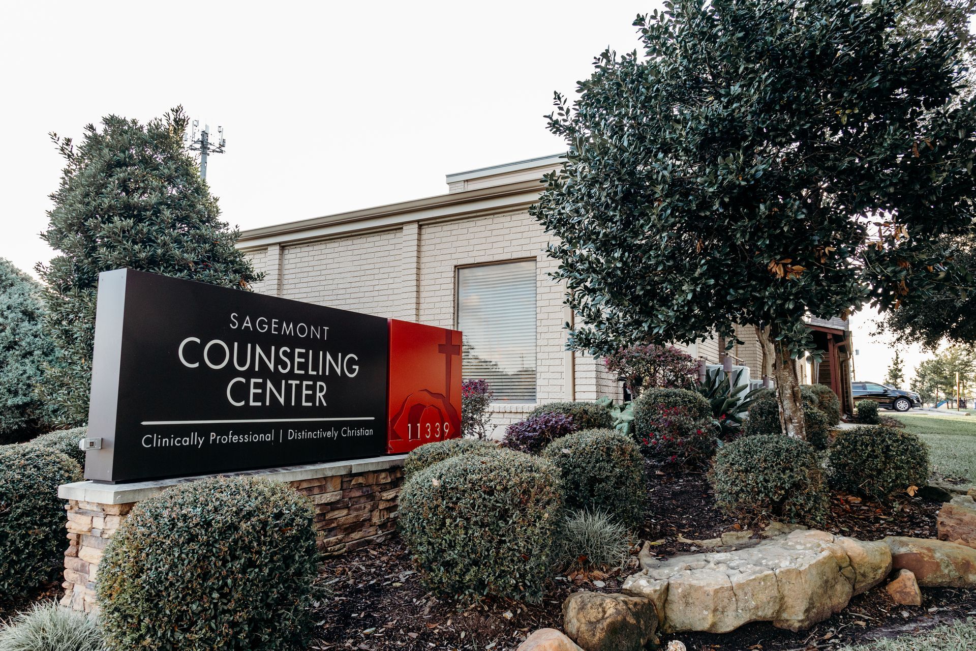 Sign for Encompass Counseling Center in front of a building with landscaping.