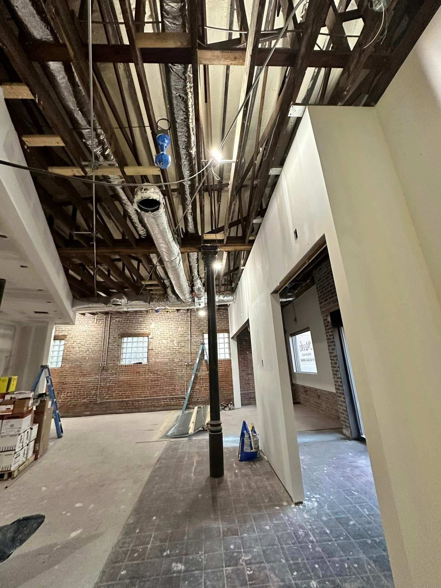A building under construction with a lot of pipes hanging from the ceiling.