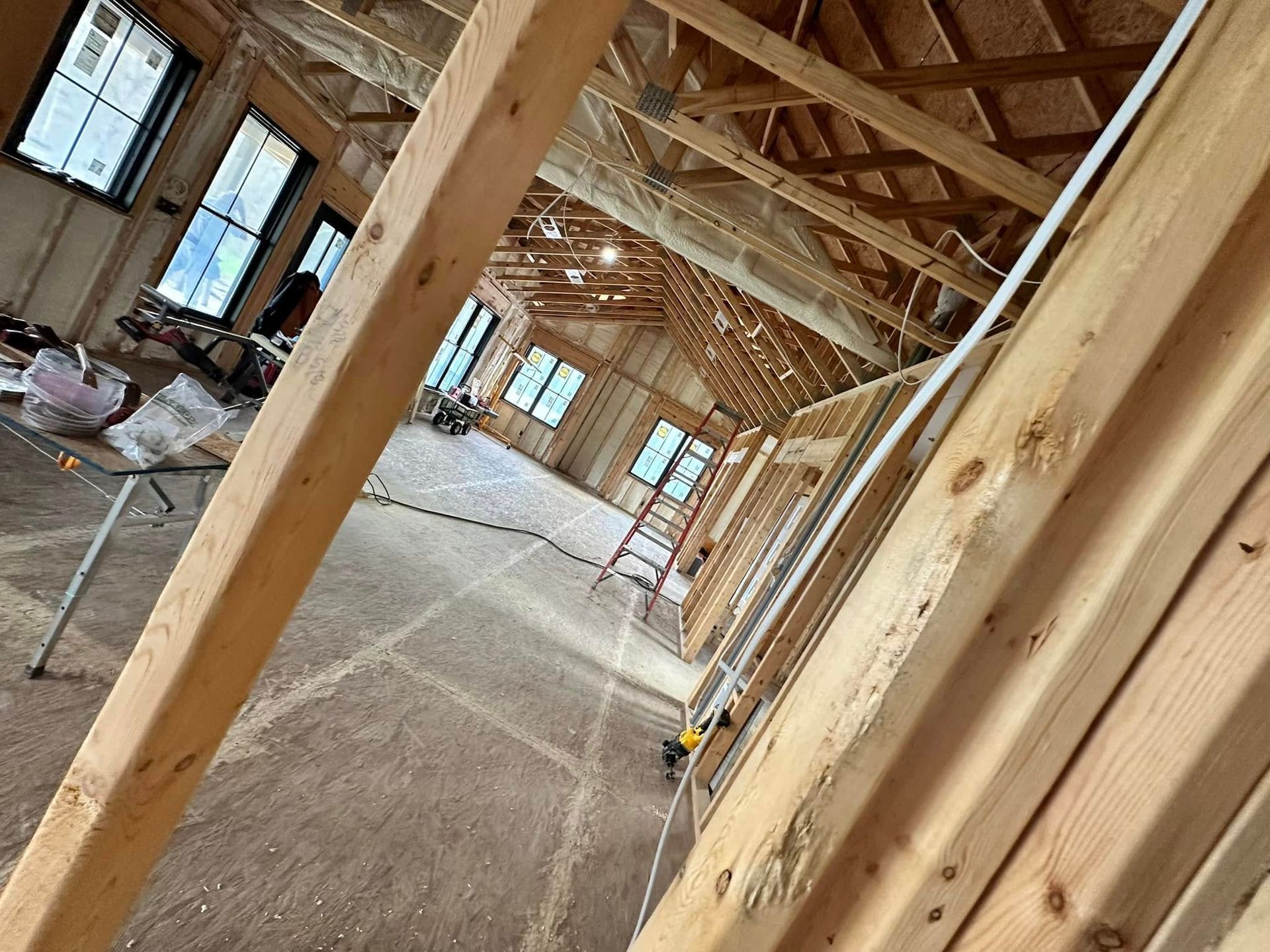A room under construction with wooden beams and a ladder.