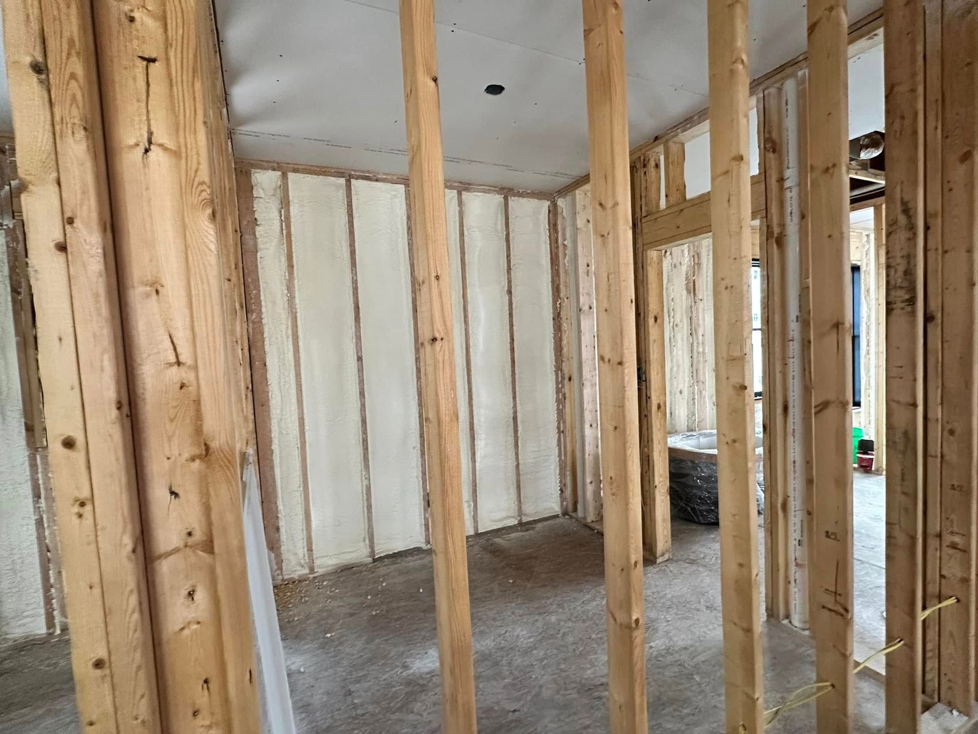 A room in a house under construction with wooden beams and insulation on the walls.