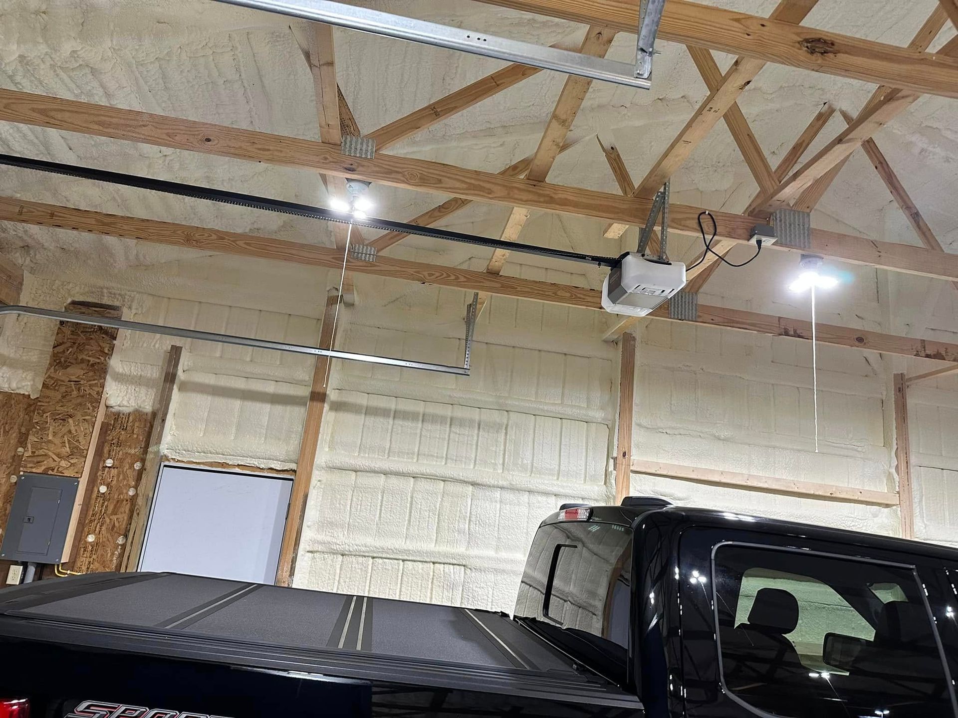 A truck is parked in a garage with a garage door opener.
