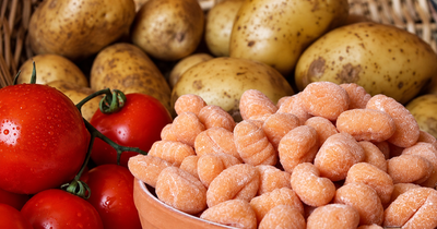 Pomodori, patate e bulbi d'aglio disposti in un'esposizione da mercato.