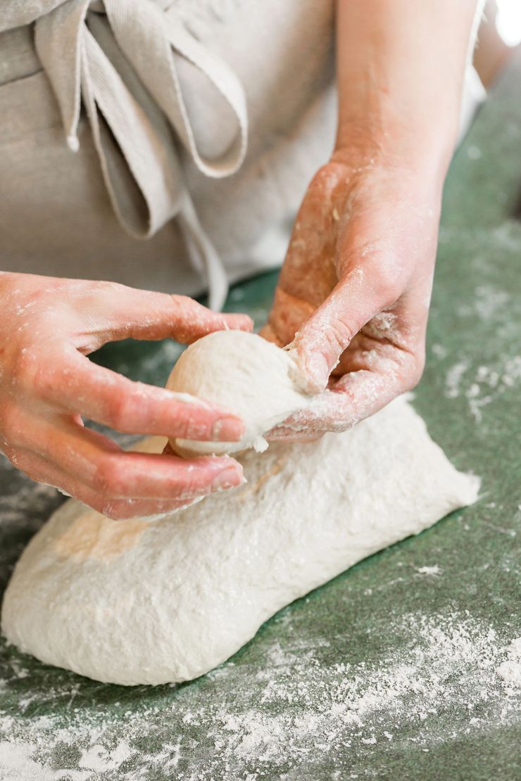 Mani che modellano l'impasto su una superficie infarinata in cucina