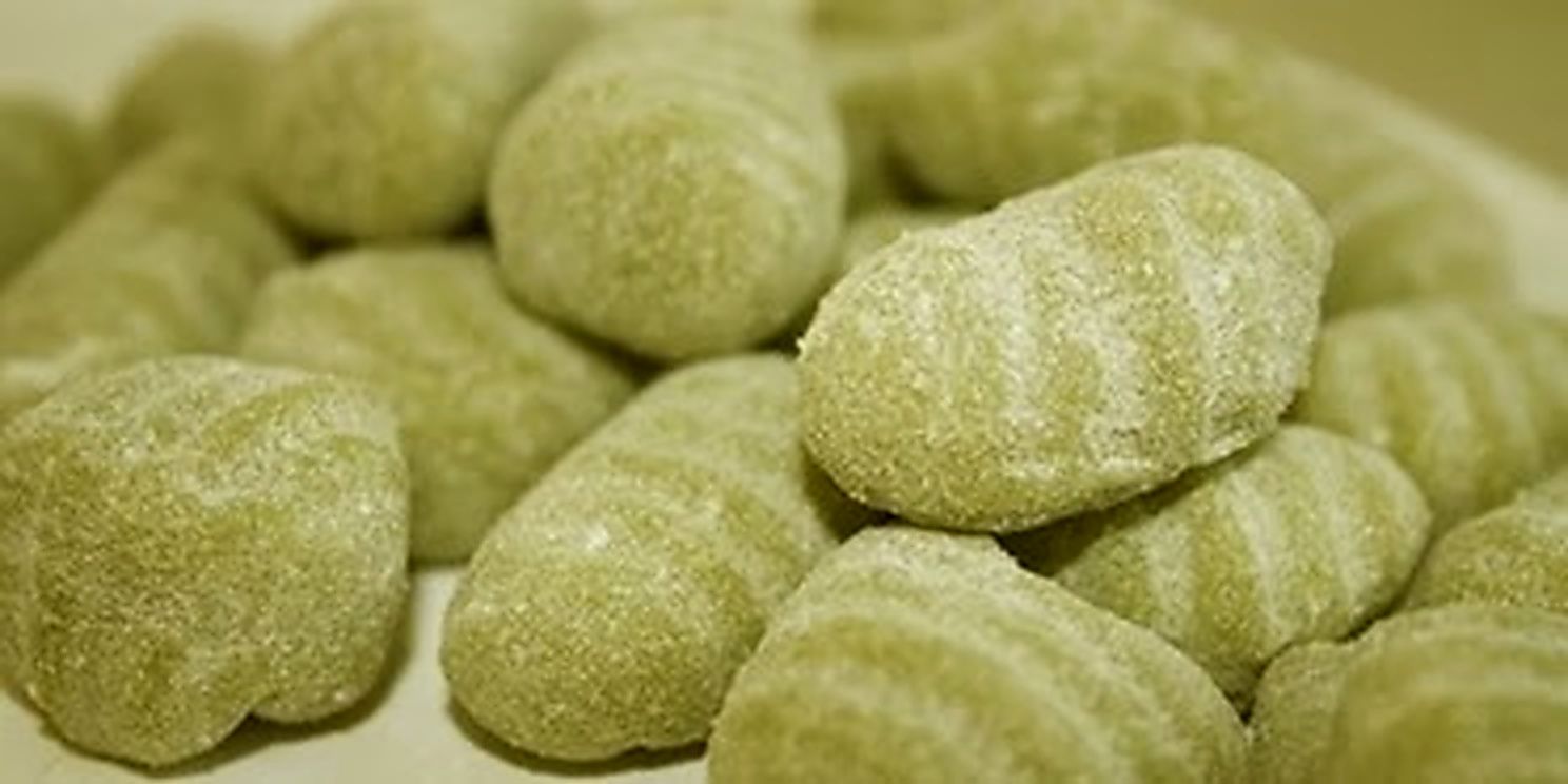Primo piano di caramelle gommose verdi ricoperte di zucchero, ammucchiate insieme.