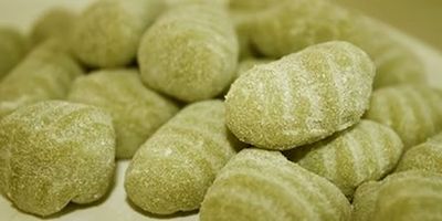 Primo piano di caramelle gommose verdi ricoperte di zucchero, ammucchiate insieme.