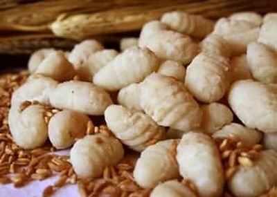 Bozzoli bianchi di baco da seta ammucchiati su un letto di chicchi o semi marroni