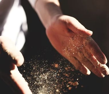 Mani che catturano particelle di polvere illuminate dal sole sospese nell'aria