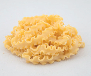 Mucchietto di pasta cruda ondulata su sfondo bianco