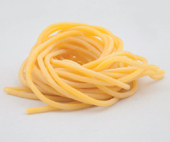 Un fascio di pasta gialla cruda su sfondo bianco