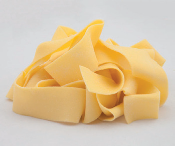 Nidi di fettuccine gialle su una superficie grigio chiaro