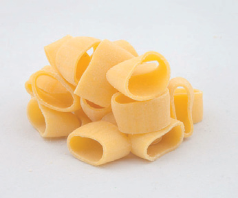 Pila di conchiglie di pasta gialla cruda su sfondo bianco