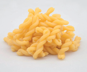 Mucchietto di pasta corta, attorcigliata e gialla su uno sfondo bianco uniforme.