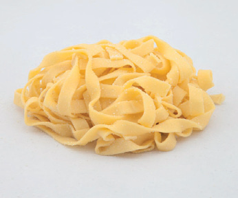 Un mucchio di tagliatelle di pasta cruda su sfondo bianco.