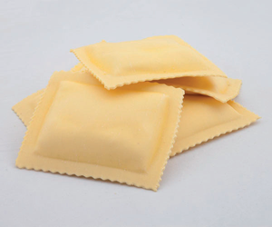 Tre quadrati di pasta ravioli cruda su uno sfondo chiaro