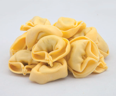 Pila di tortellini crudi su sfondo bianco